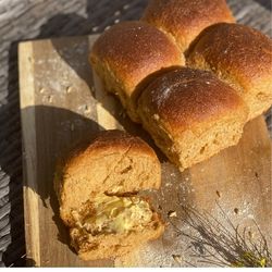 Picture of freshly baked rolls made with freshly ground grains. One roll cut opened and with grass fed butter inside.