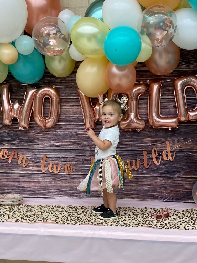 little girl in two wild party tutu in fron of two wild birthday party backdrop