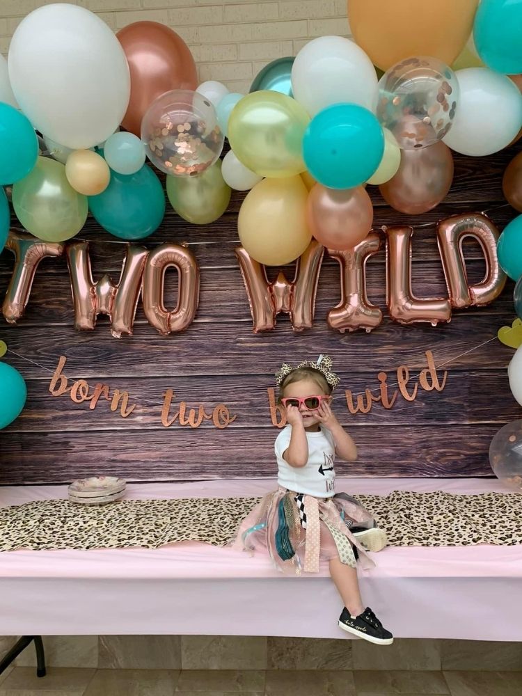 little girl sitting in front of two wild party backdrop