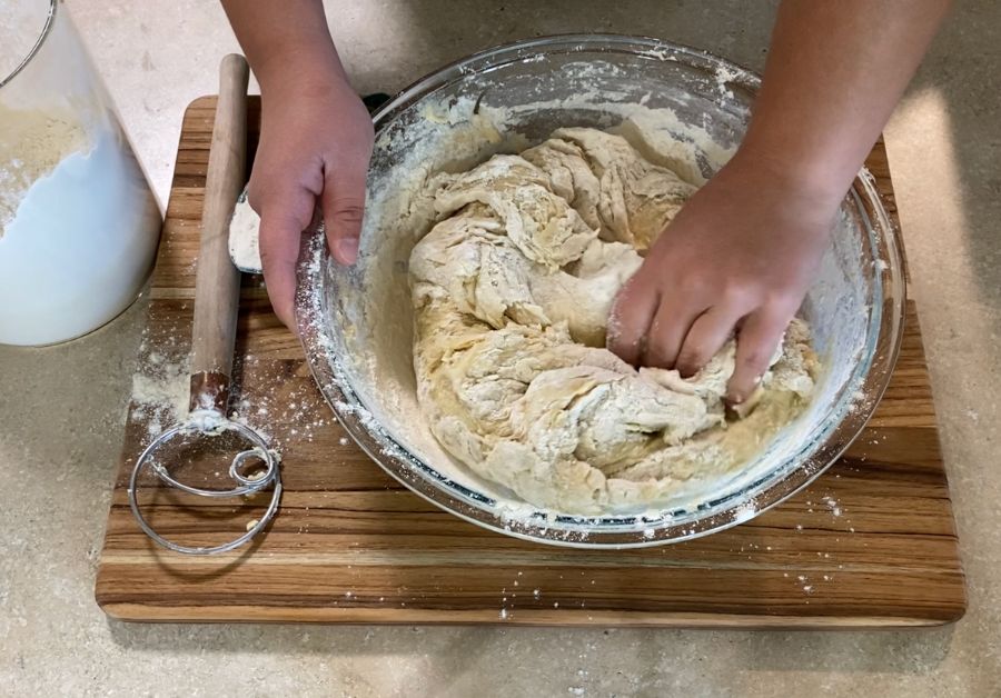hands kneading dough inside bowl