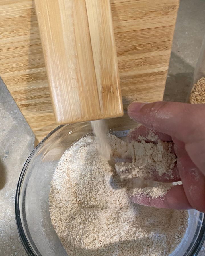 grains beeing gound into flour hand feeling texture of flour