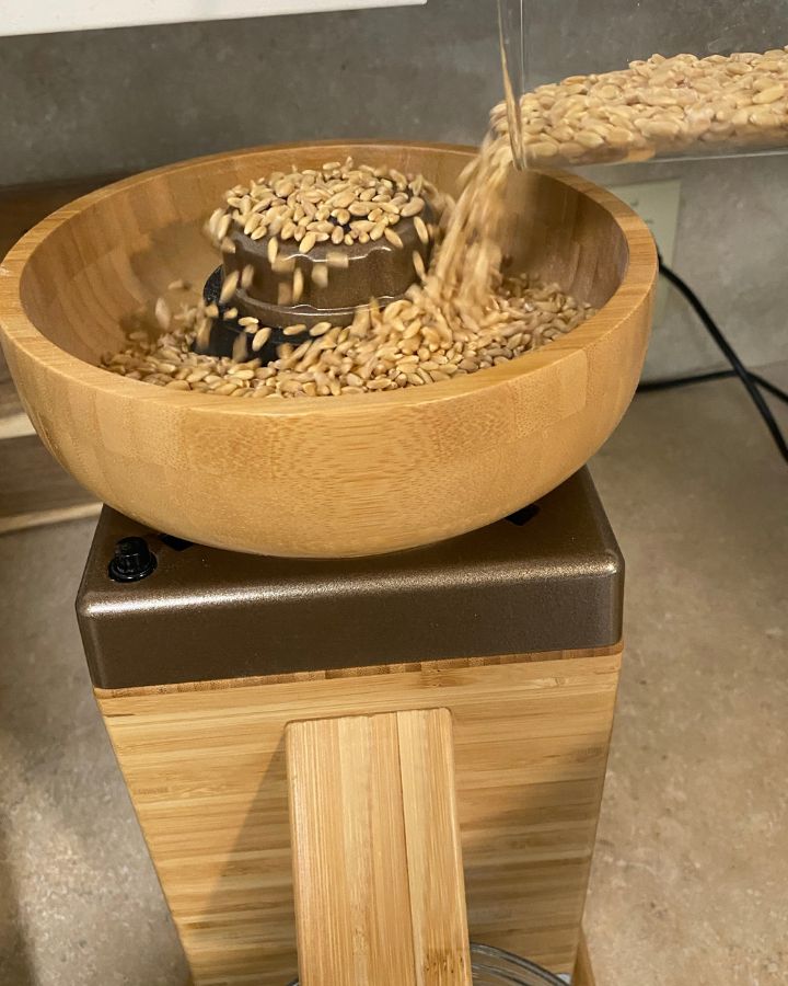 pouring wheat berries into grain mill