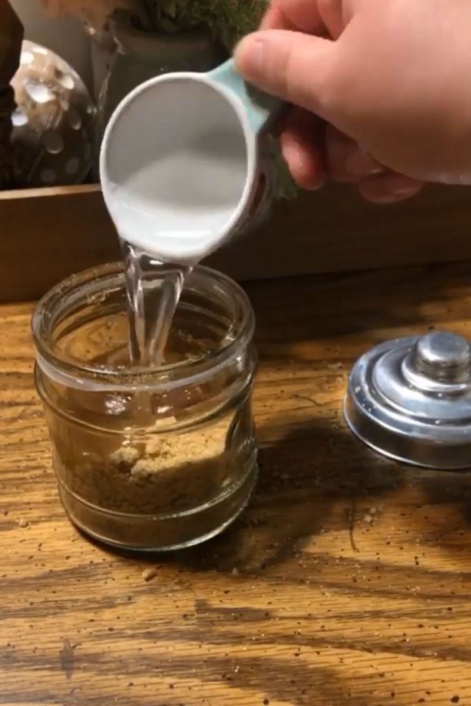 pouring melted coconut oil into jar with sugar