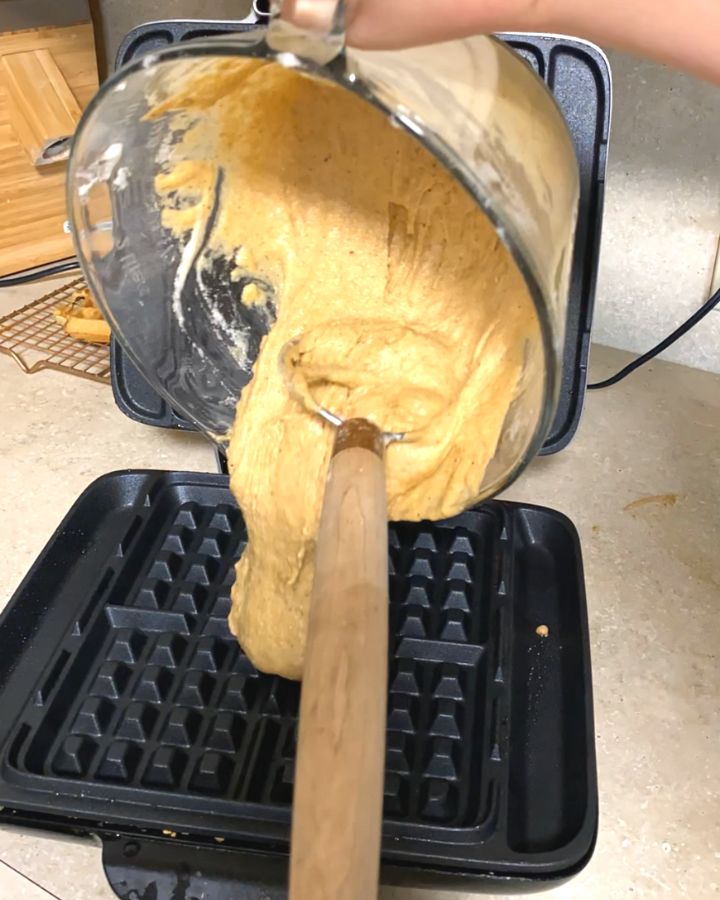 pouring ezekiel waffle batter into heated waffle iron.