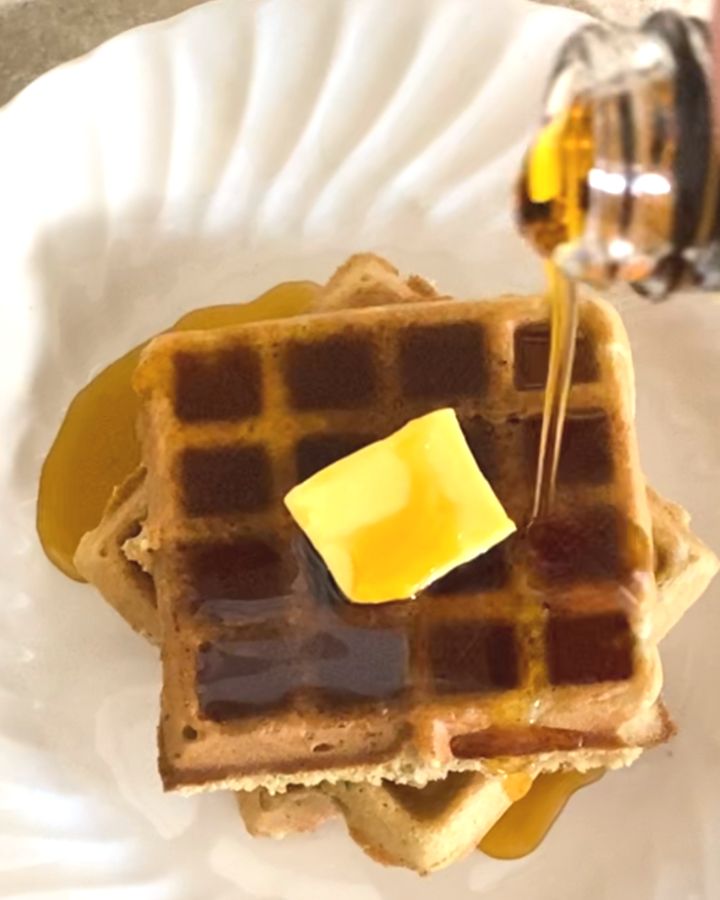 Drizzling maple syrup on a stack of waffles