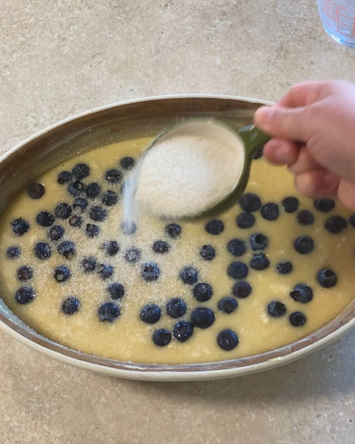 sprinkling sugar onto cobbler cake before putting it into oven.