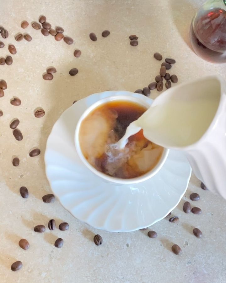 Pouring raw cream into hot coffee.